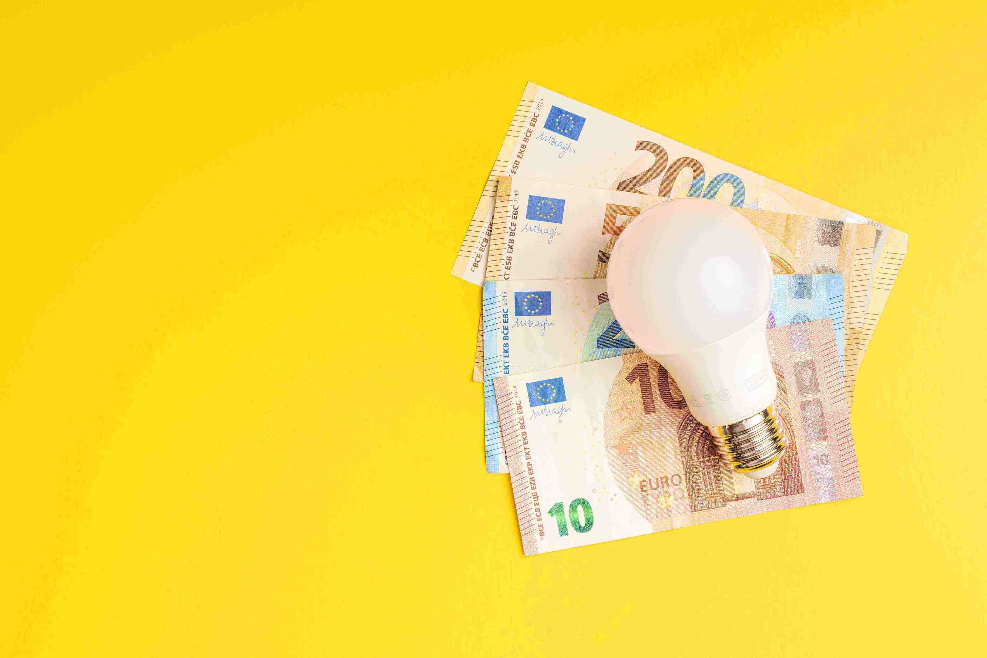 Foto di una lampadina appoggiata su delle banconote.