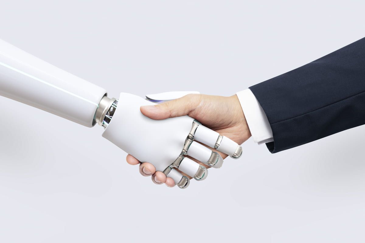 Unione tra intelligenza artificiale e aziende: mano umana stringe mano robotica.